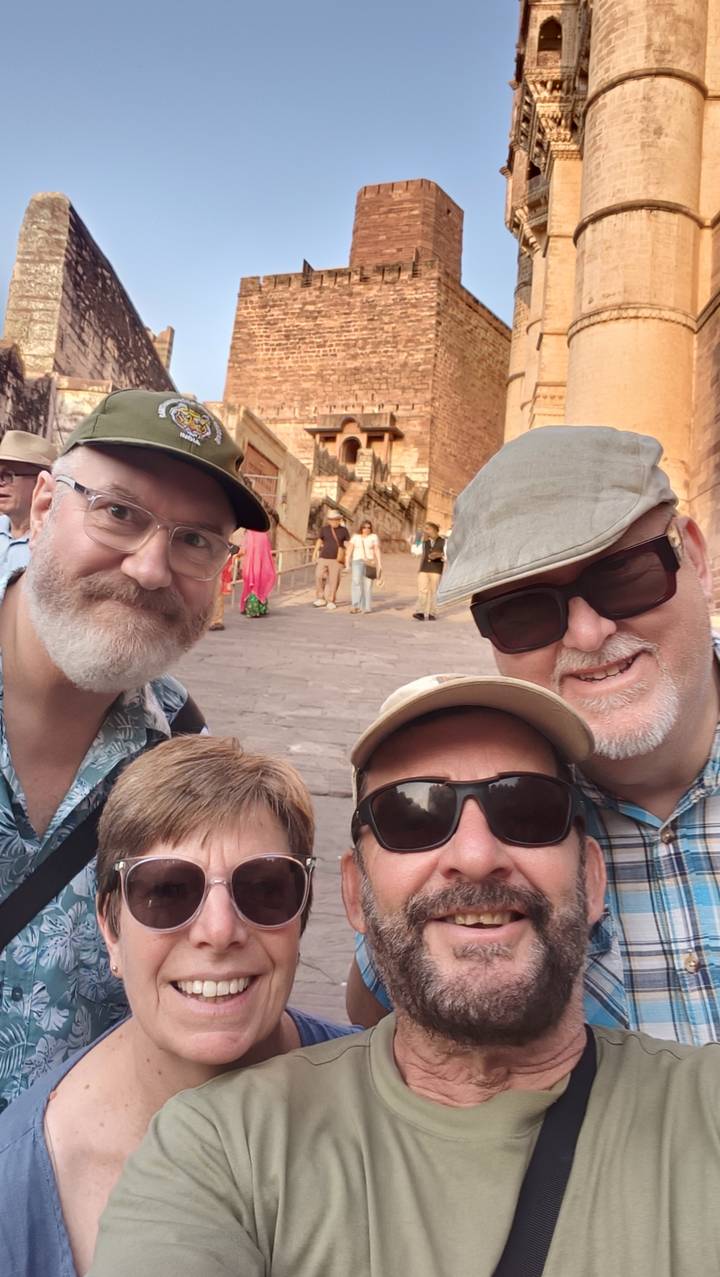 Selfie of travellers in historic fort alley with sandstone walls behind.