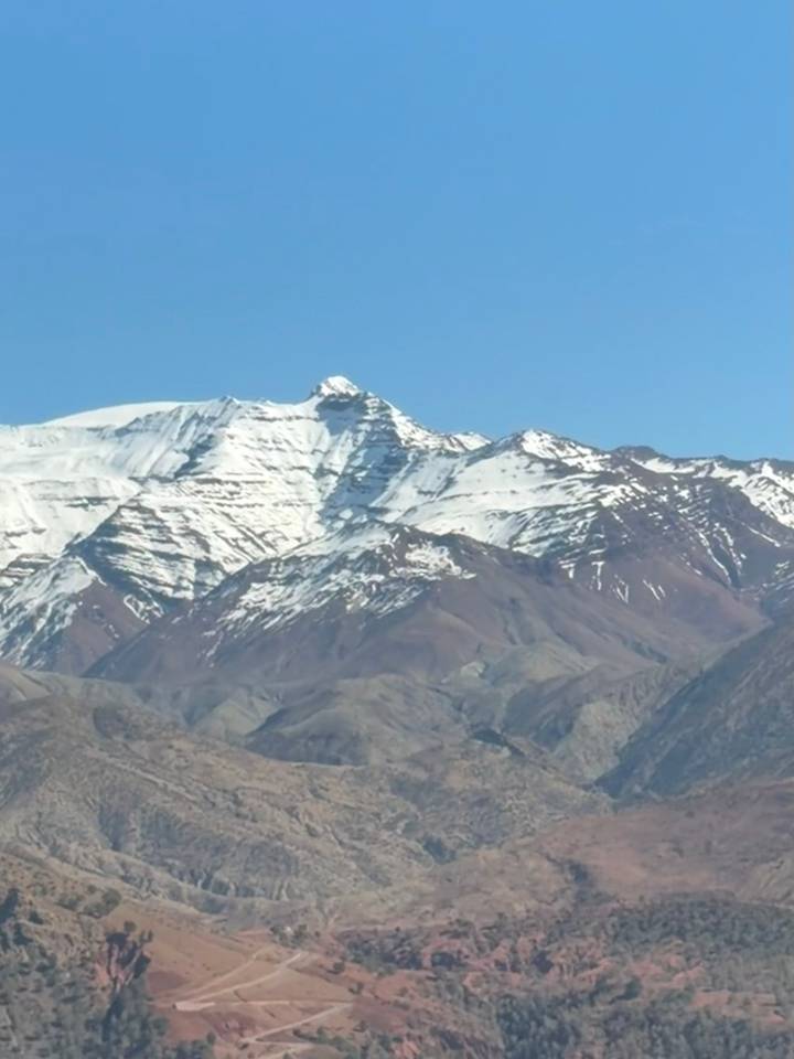Snow-capped peaks of the High Atlas Mountains under a clear blue sky.