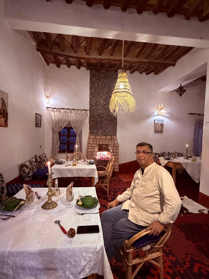 Man dining by candlelight in a warmly lit room with traditional decor and a stone fireplace.