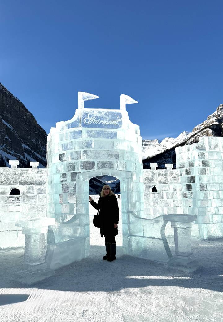 A woman stands at the entrance of a translucent ice castle bearing the Fairmont name.