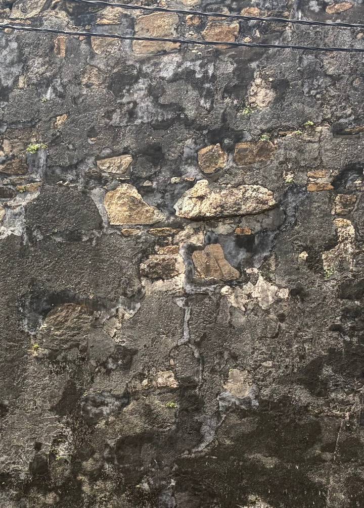 Detail of an old weathered stone wall showing rough textures and patches of different colored stones.