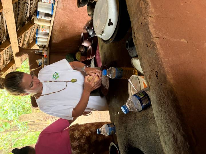 Closer angle of the same traveller kneading ingredients at a countryside cooking workshop.