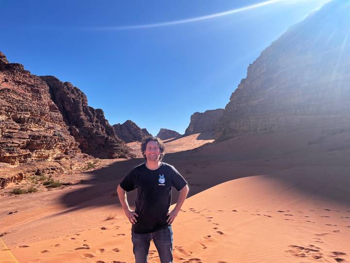 Traveler stands confidently between towering sandstone walls in Wadi Rum’s sweeping desert valley.
