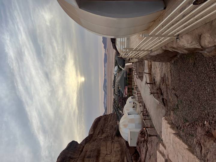 Desert camp with white domes and pathways set against a muted sky in Wadi Rum.