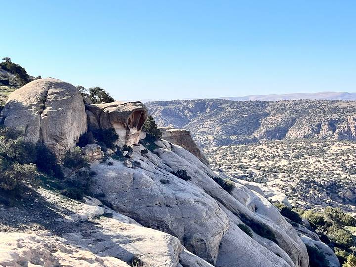 Wide rocky vista dotted with shrub-covered slopes and the skull rock in the distance.