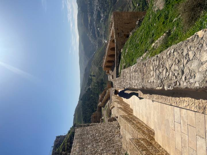Child climbs along the stone walkway of an ancient hilltop fortress with valleys beyond.