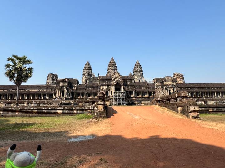 Front view of majestic Angkor Wat temple complex under cloudless blue sky, with scaffolding on central causeway.