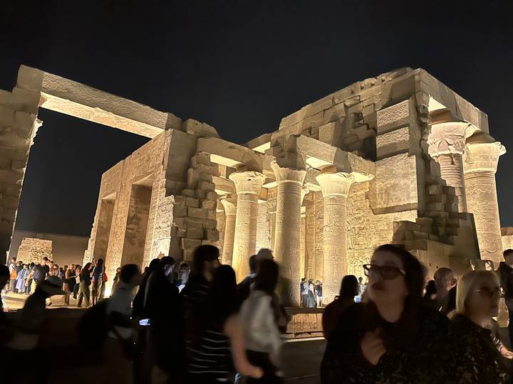 Nighttime view of Kom Ombo Temple lit with golden spotlights crowded with visitors