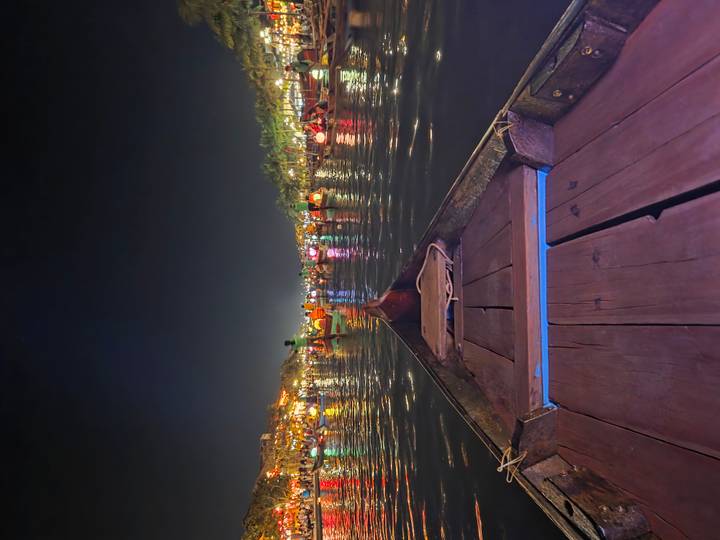 Colorful lantern-lit boats crowd the river in Hoi An during a vibrant night festival, viewed from a wooden canoe