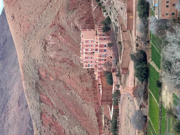 Isolated kasbah-style hotel set against rugged red mountains and terraced fields