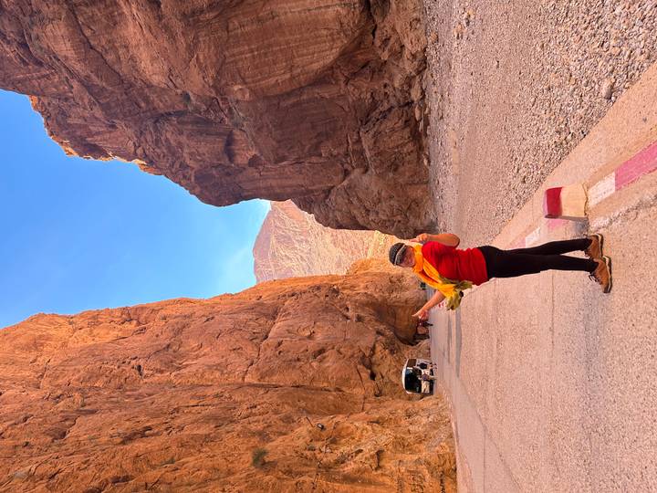 Traveler standing triumphantly in the narrow orange cliffs of Todra Gorge