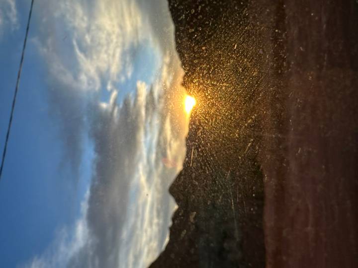 Hazy sunset dipping behind mountain silhouettes seen through a dusty window