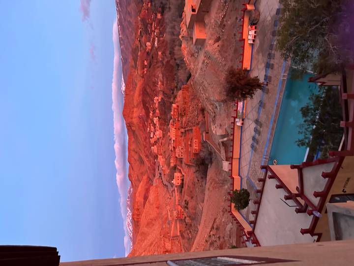 Sunset light bathes red-hued hills above a hotel pool terrace