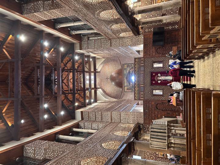 Wood-beamed interior of Cairo’s Hanging Church with visitors observing the altar