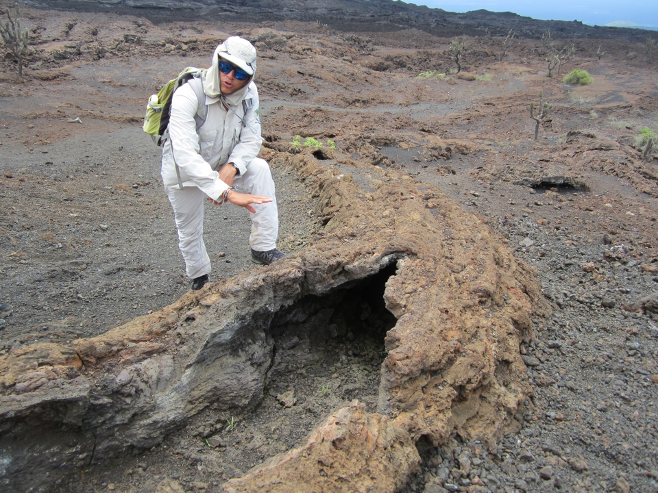 Personne examinant une formation rocheuse volcanique.
