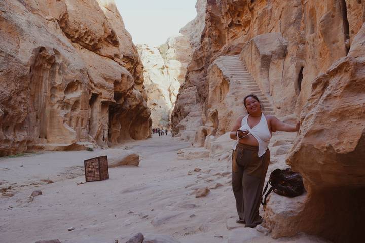 Woman smiles while exploring the narrow sandstone gorge entrance of Petra.