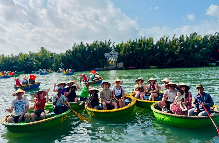 Tour group paddling round basket boats on a green river lined with dense palm forest