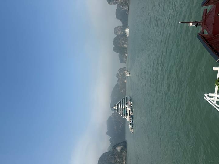 Cruise ships scattered across the calm blue waters of Ha Long Bay on a clear day.
