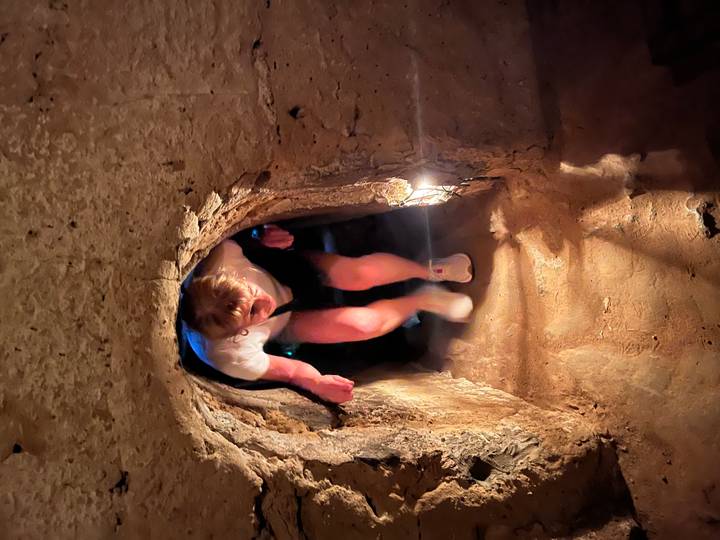 Visitor crouches through a narrow, dimly lit tunnel in the historic Cu Chi network.