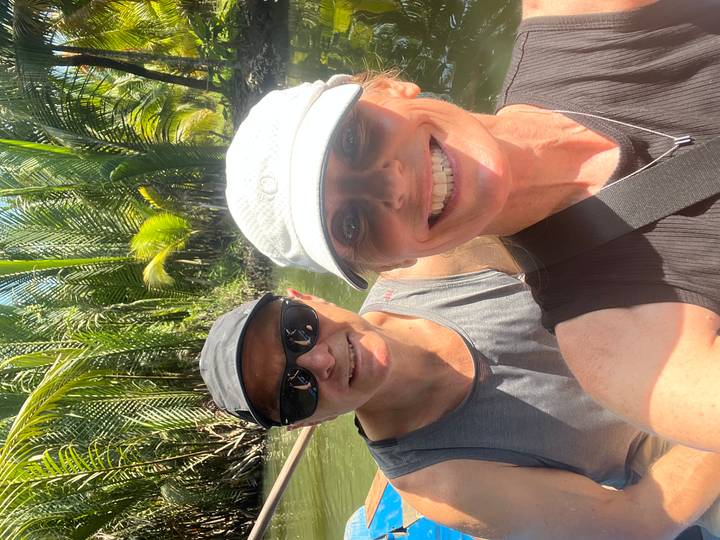 Selfie of two tourists in a small boat amid lush palms of the Mekong Delta.