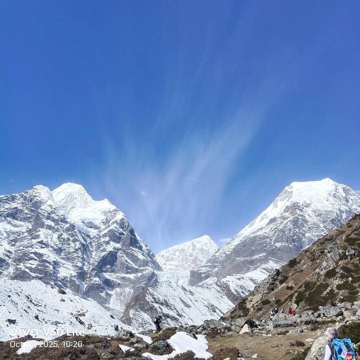 Panoramic view of twin snow peaks against a deep blue Himalayan sky.