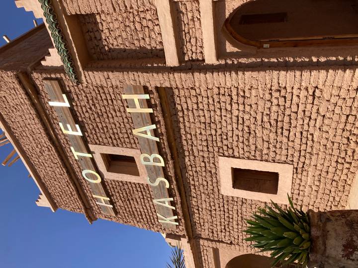 Close view of adobe brick wall with large letters spelling 'HOTEL KASBAH'.