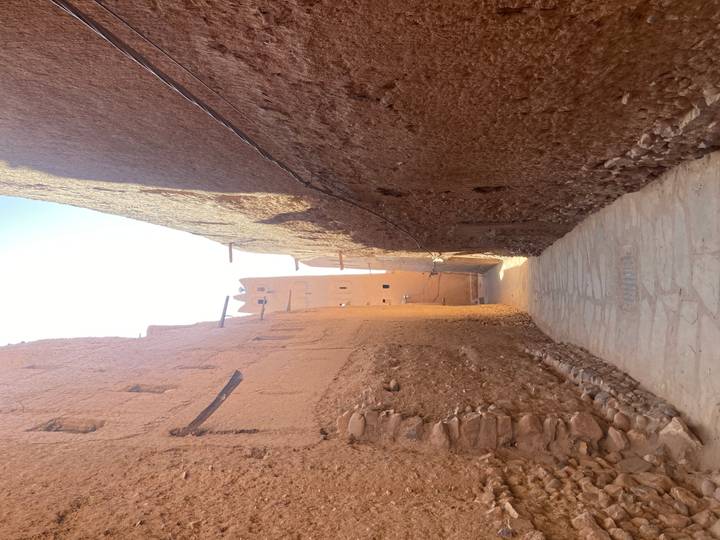 Sun-lit narrow alleyway between high earthen walls of a desert village.