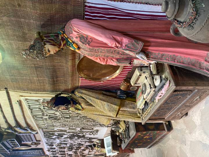 Display of traditional Berber clothing and antique weapons inside a small desert museum.