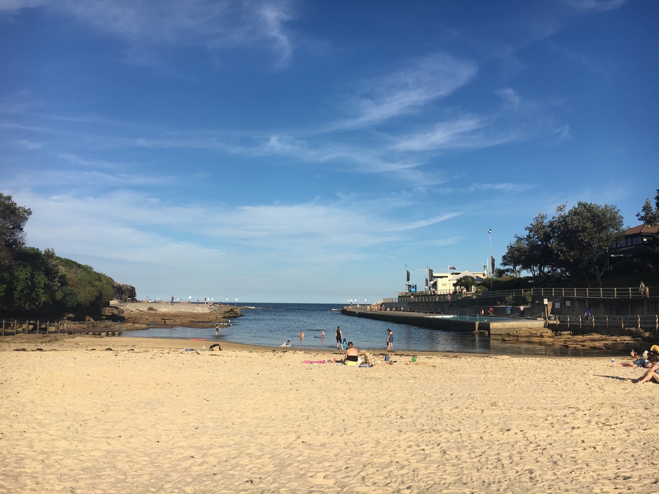 Calm bay with sandy beach and few people around.