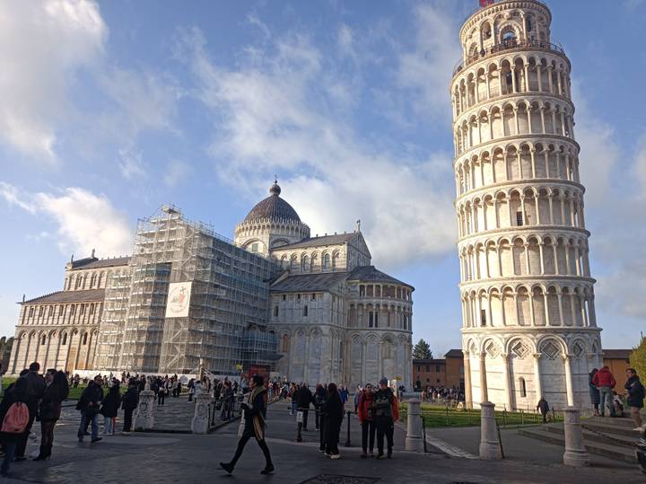 The Leaning Tower of Pisa and Pisa Cathedral rise above a busy square filled with visitors.
