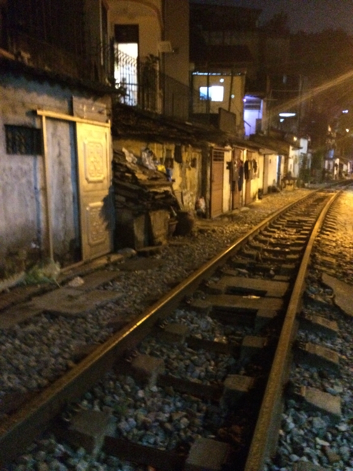 Voie ferrée traversant une rue étroite la nuit.