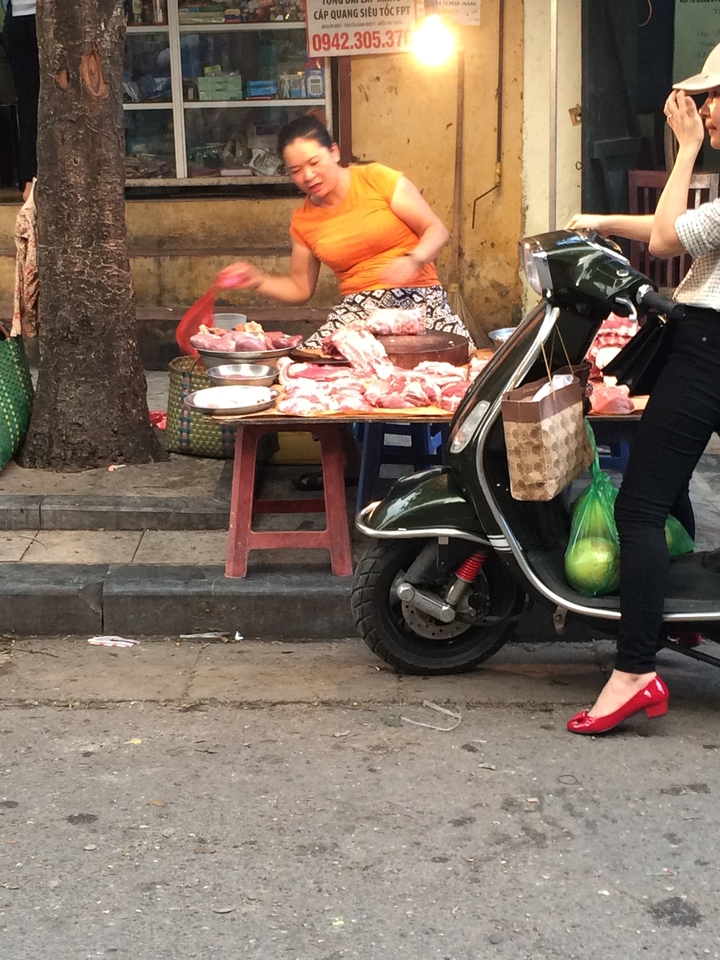 Vendeur de rue vendant de la viande à côté d'un scooter garé.