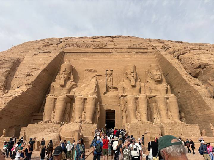 Grand façade of Abu Simbel with colossal statues of Ramses II towering over crowds at the entrance.