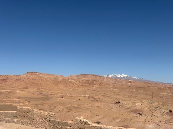 Vast arid Moroccan plateau with distant snow-capped mountain under a clear blue sky.