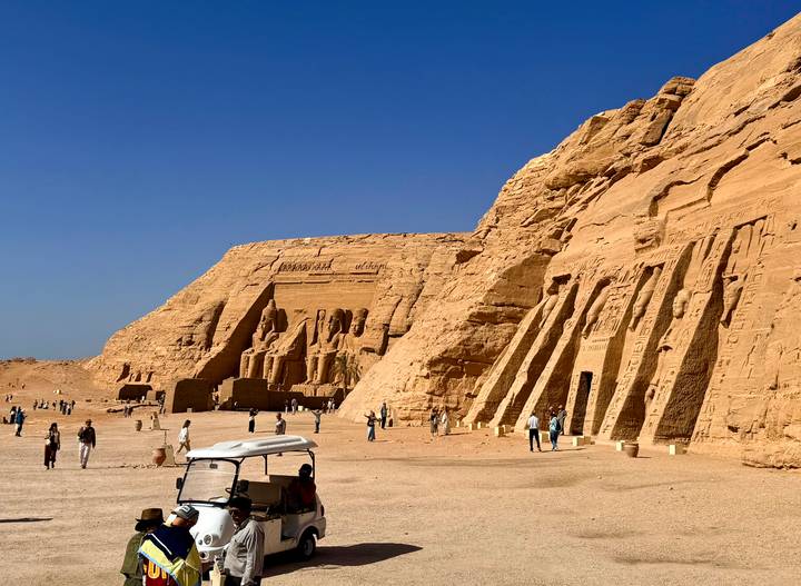 The temples of Abu Simbel under clear desert skies with visitors below.