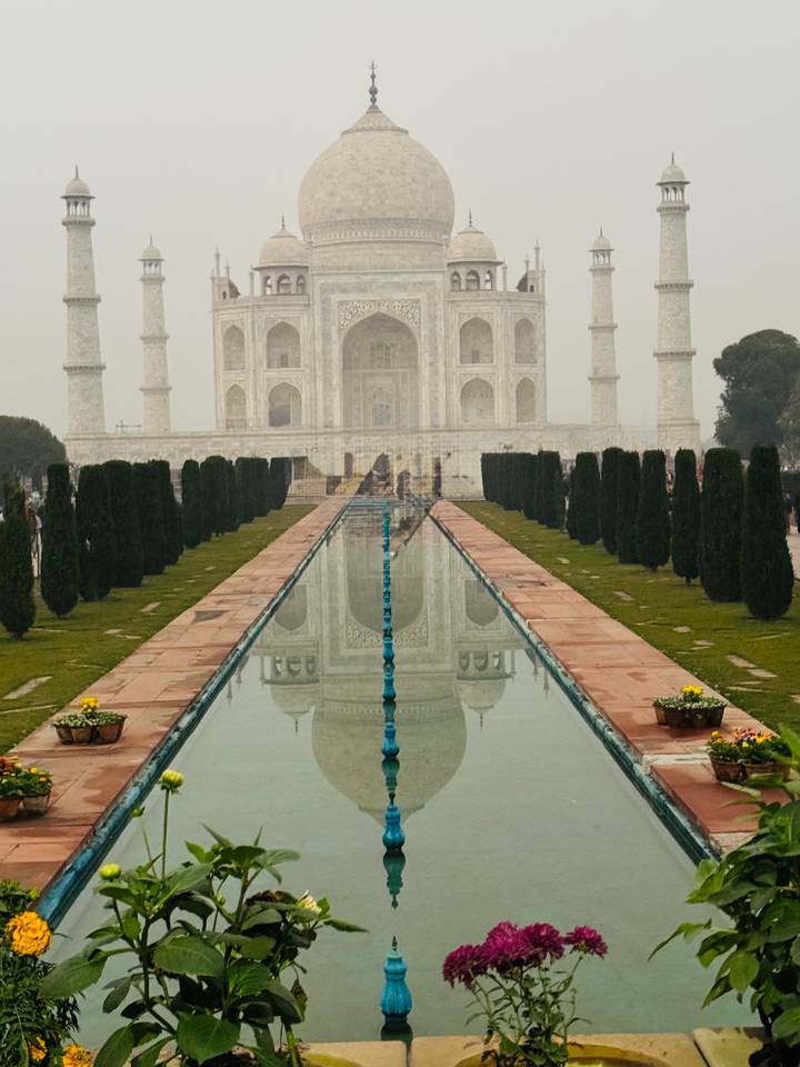 Classic frontal view of the Taj Mahal reflected in its long pool on a hazy day