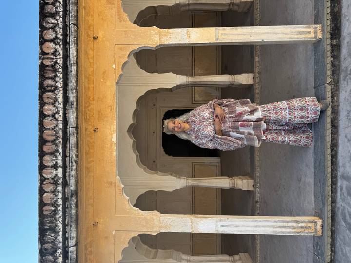 Woman in patterned outfit standing under arched entrance of historic courtyard