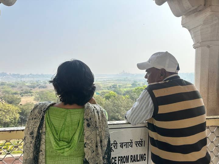 Man and woman lean on balcony railing admiring hazy distant view of river plain