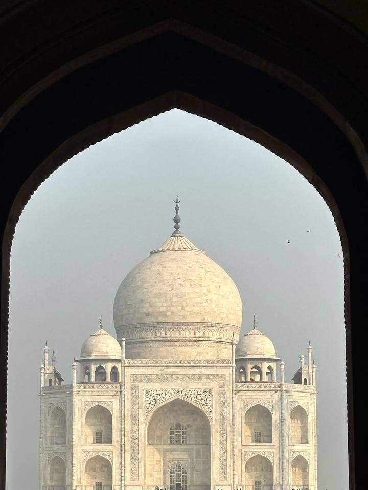 Close frame of Taj Mahal dome seen through dark arched window