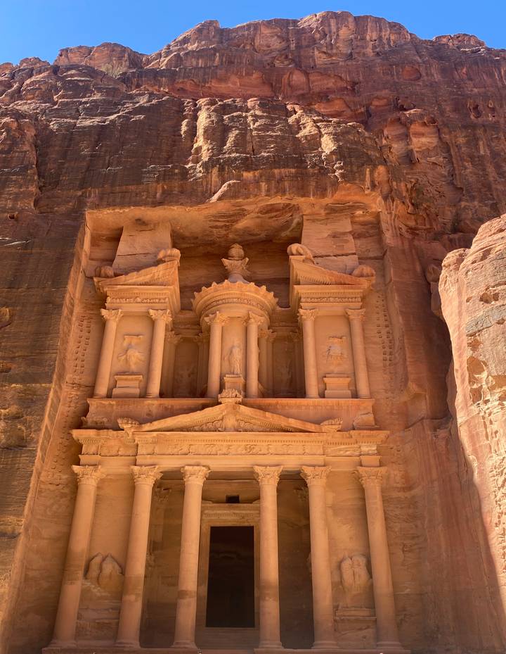 Detailed façade of the Treasury at Petra carved into rose-red sandstone cliffs basking in natural light.