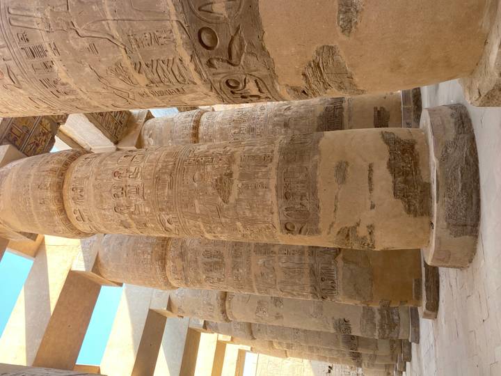 Gigantic sandstone columns covered in hieroglyphs inside the hypostyle hall of Karnak Temple.
