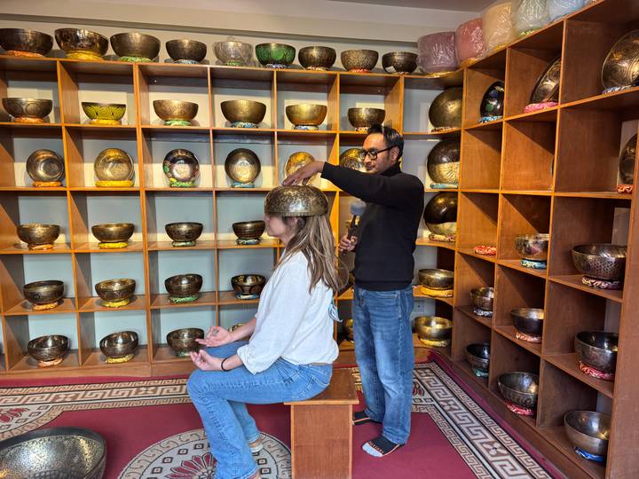 Sound-healing demonstration with a singing bowl placed on a seated visitor’s head.