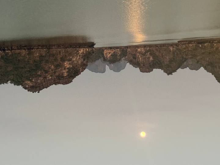 Dusk view of limestone karsts in Halong Bay under a rising full moon.