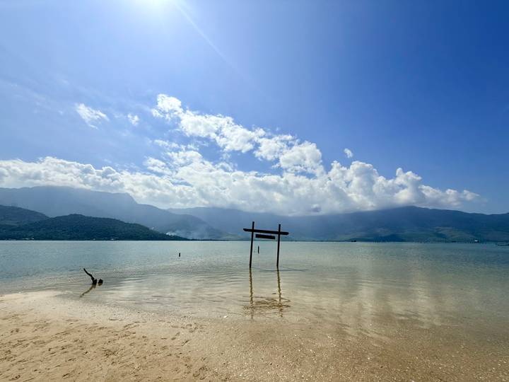 Crystal clear shallows of a lagoon with mountains under bright midday sun.