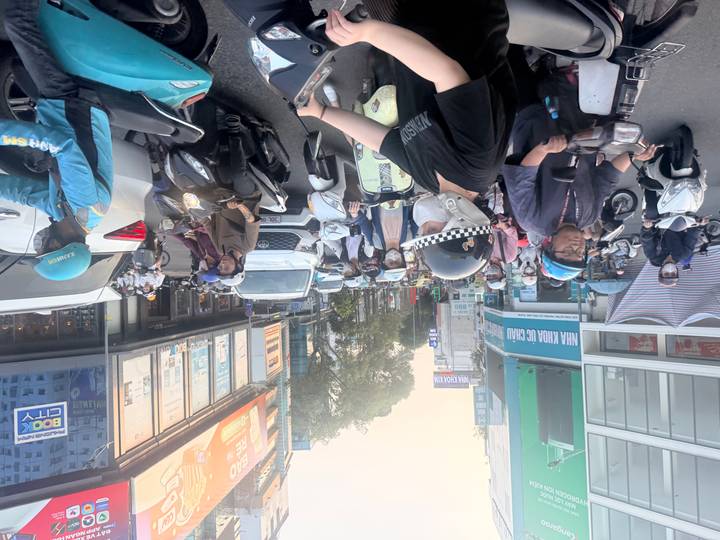 Busy Vietnamese city street filled with motorbikes, cars and riders wearing helmets and masks.