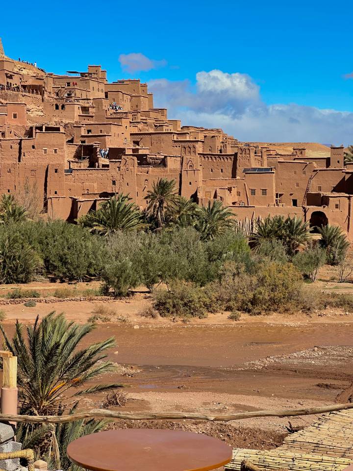 Historic earthen kasbah of Ait Benhaddou with palm groves in the foreground.