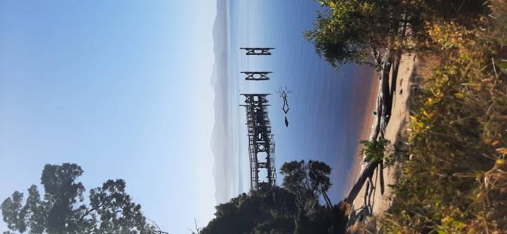 A quiet wooden jetty extends over perfectly still lake waters with hazy mountains in the distance.