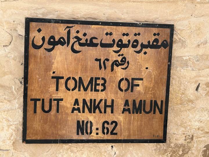 Wooden plaque sign indicating Tomb of Tutankhamun No. 62 with Arabic script.