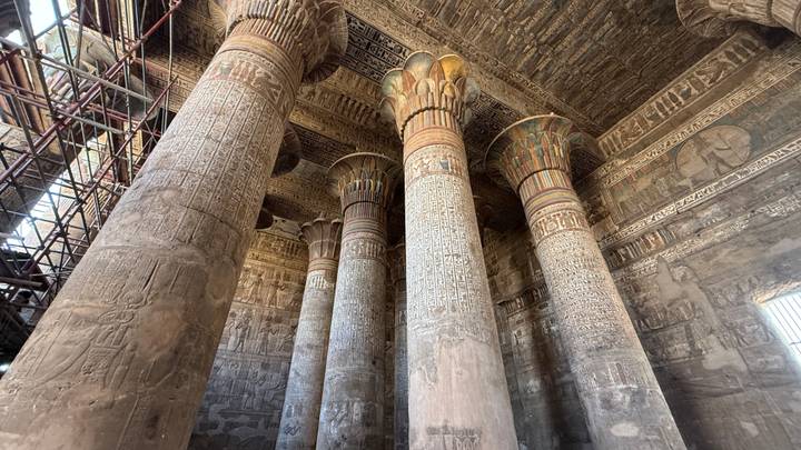 Grand hypostyle hall with towering decorated columns and intricate ceiling carvings.