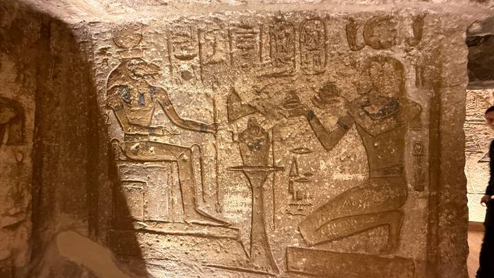Low-light photo of carved relief inside a narrow ancient tomb chamber.